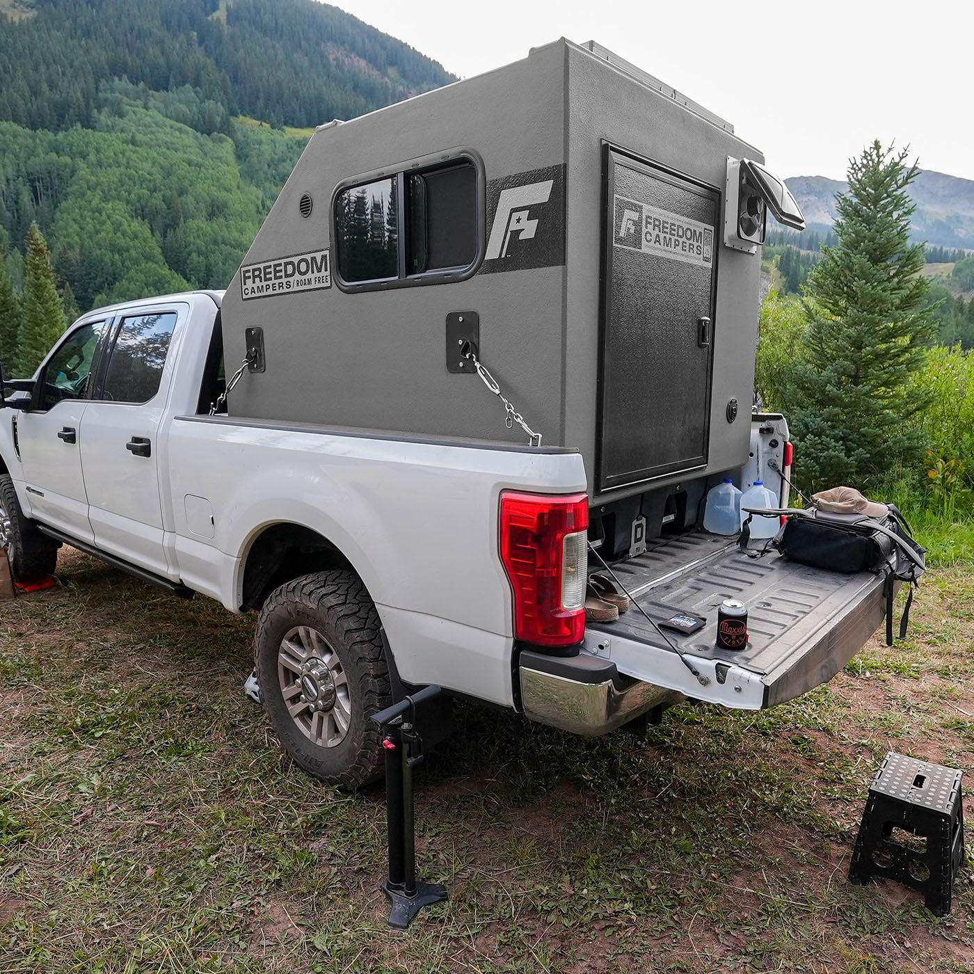 Camper in a F-250 truck bed on top of a platform, tied down with the included turnbuckle mounts.