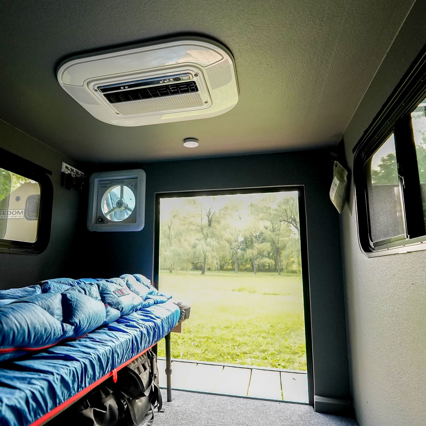 Inside the Freedom Camper showing bed, fan, and air conditioning